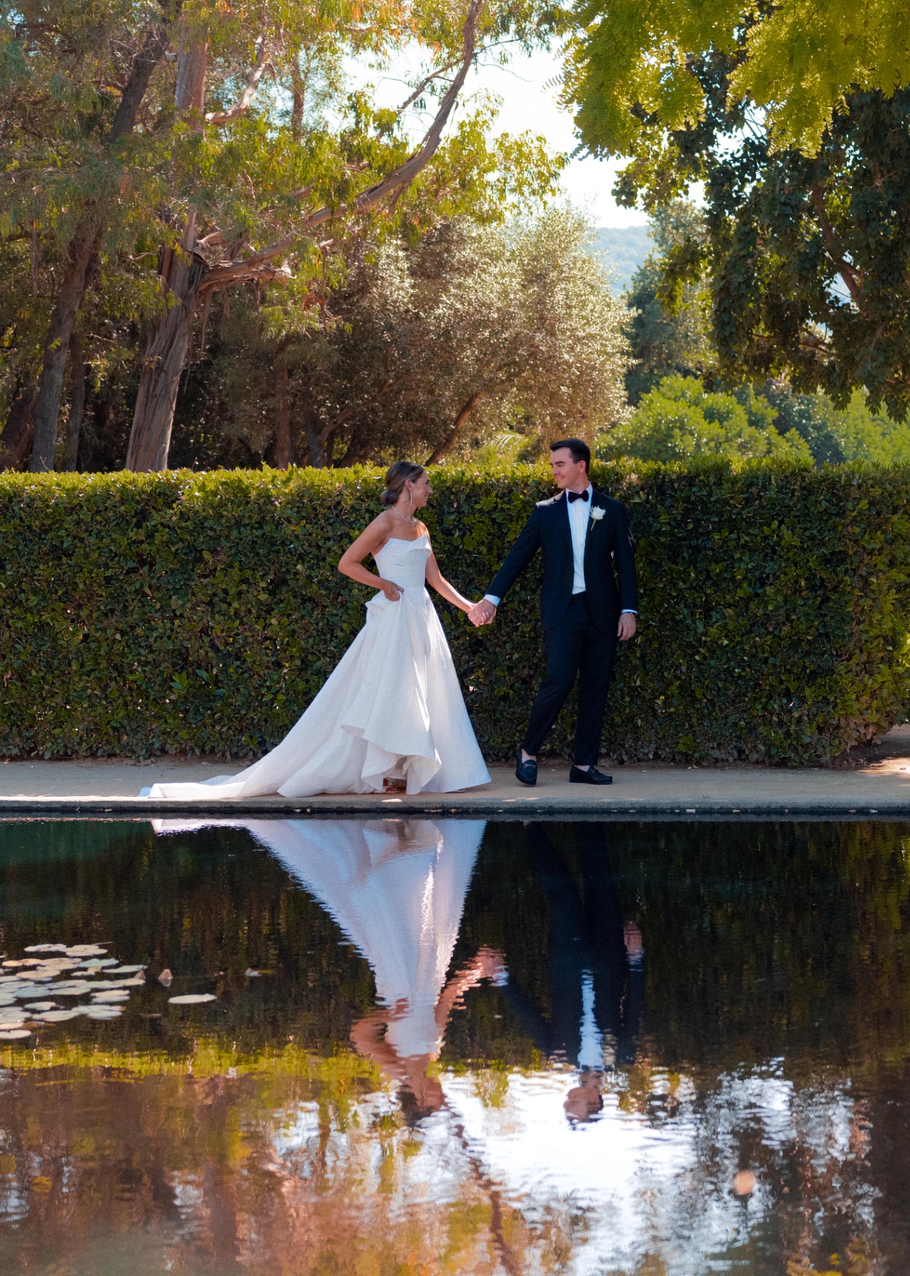 hand in hand, by the reflecting pool — documentary wedding photograph by Norah Joy, Bay Area wedding photographer
